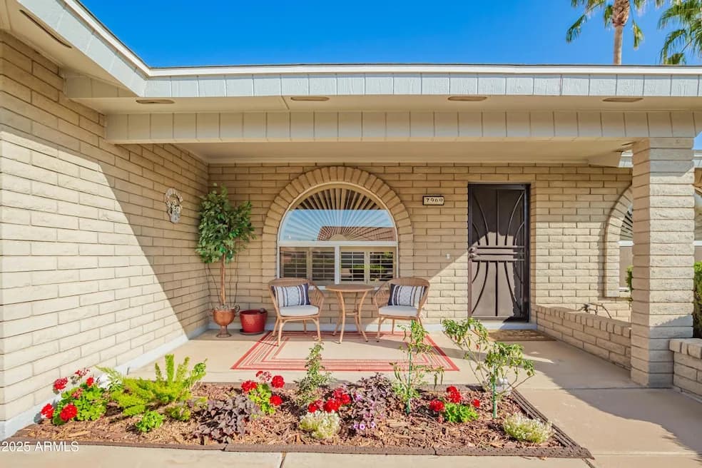Front entry of an Arizona home with an arched window and flower bed