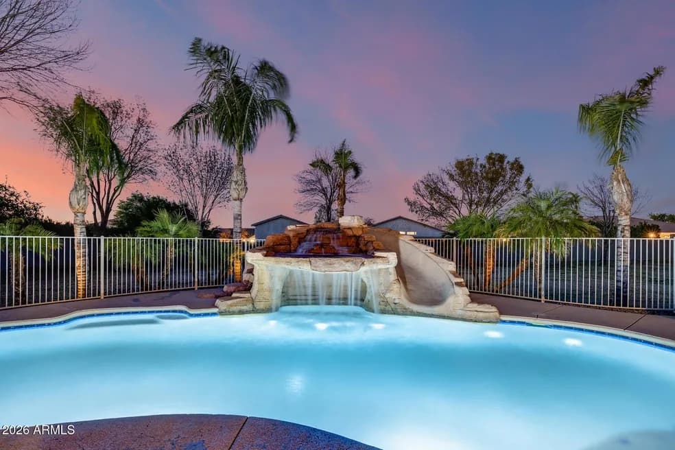 Arizona backyard pool with a rock waterfall feature at dusk