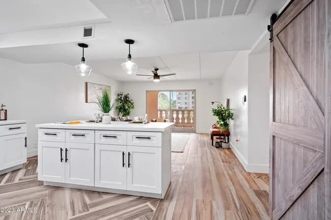 Renovated kitchen with a white island, pendant lights and a barn door